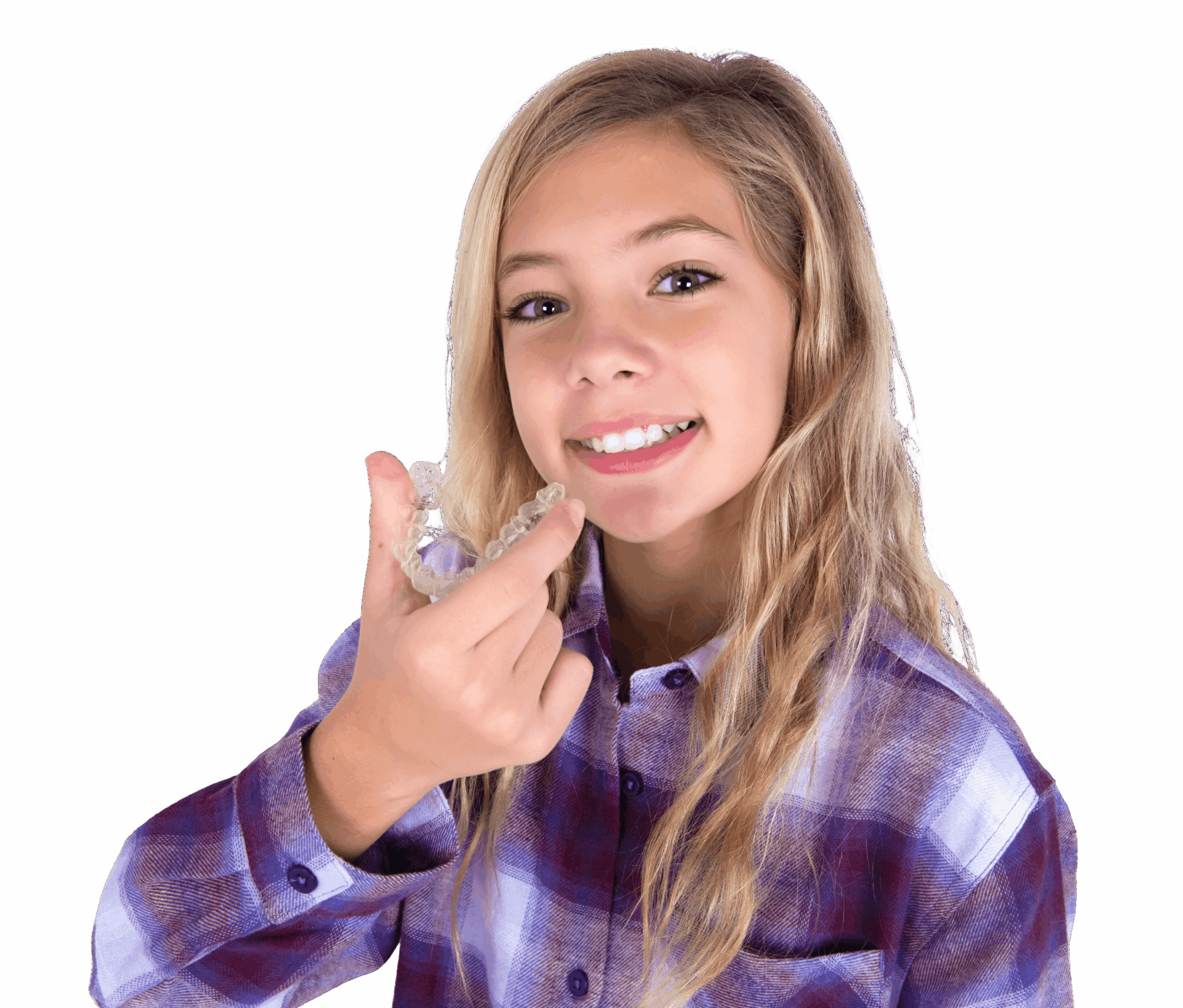 A girl with long blonde hair smiles while holding a clear aligner in her right hand. She is wearing a plaid shirt and is positioned against a white background.